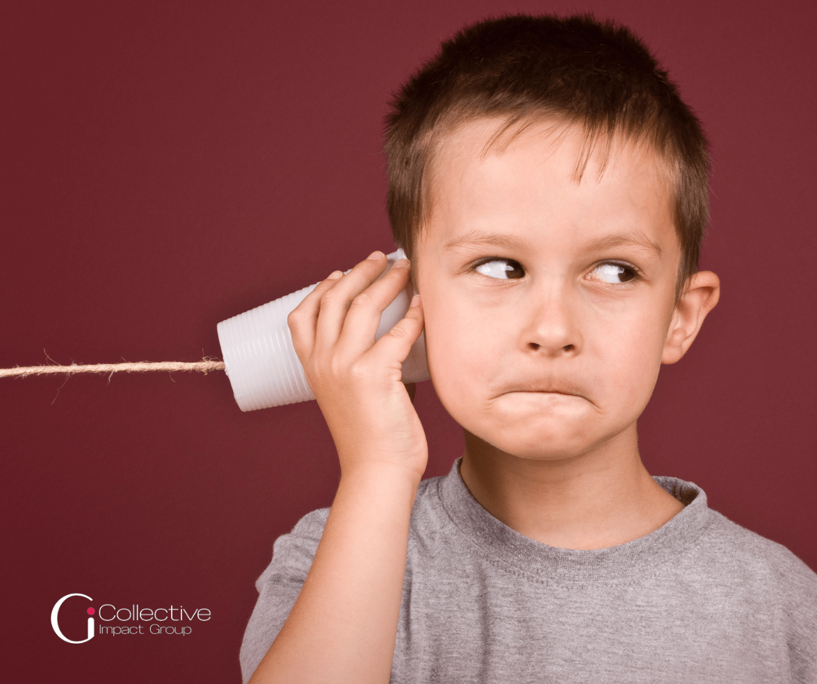 Little boy looking to the right holding a cup with a string going through it, like the old "Telephone" game